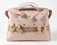 A light pink fabric handbag with double top handles, a decorative lace band, and two gold satin bows on the front, photographed against a plain white background.