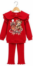 Load image into Gallery viewer, A red two-piece girls' outfit set consisting of a long-sleeve sweatshirt and matching pants, displayed on a wooden hanger against a white background. The sweatshirt features a large ruffled collar, a central graphic of a teddy bear and perfume bottle embellished with rhinestones, and matching ruffled cuffs and hem.